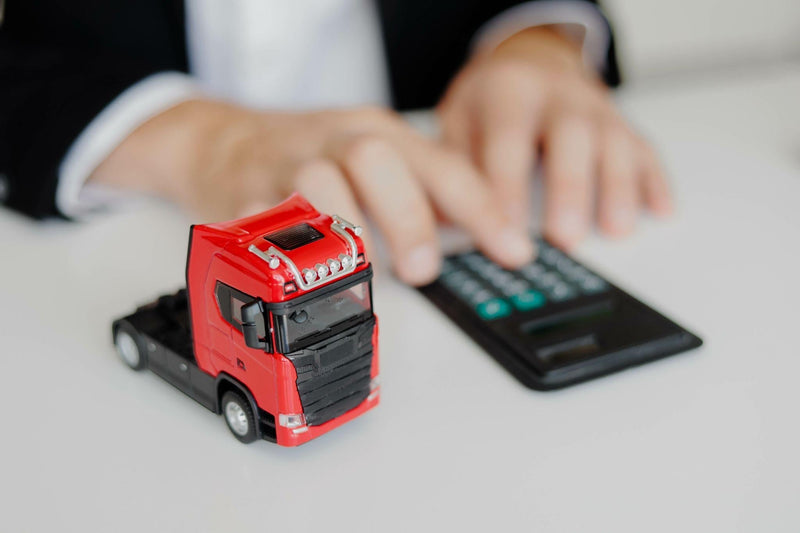 Businessman working in office with calculator. Calculation of logistics costs. Toy cargo truck on the table.