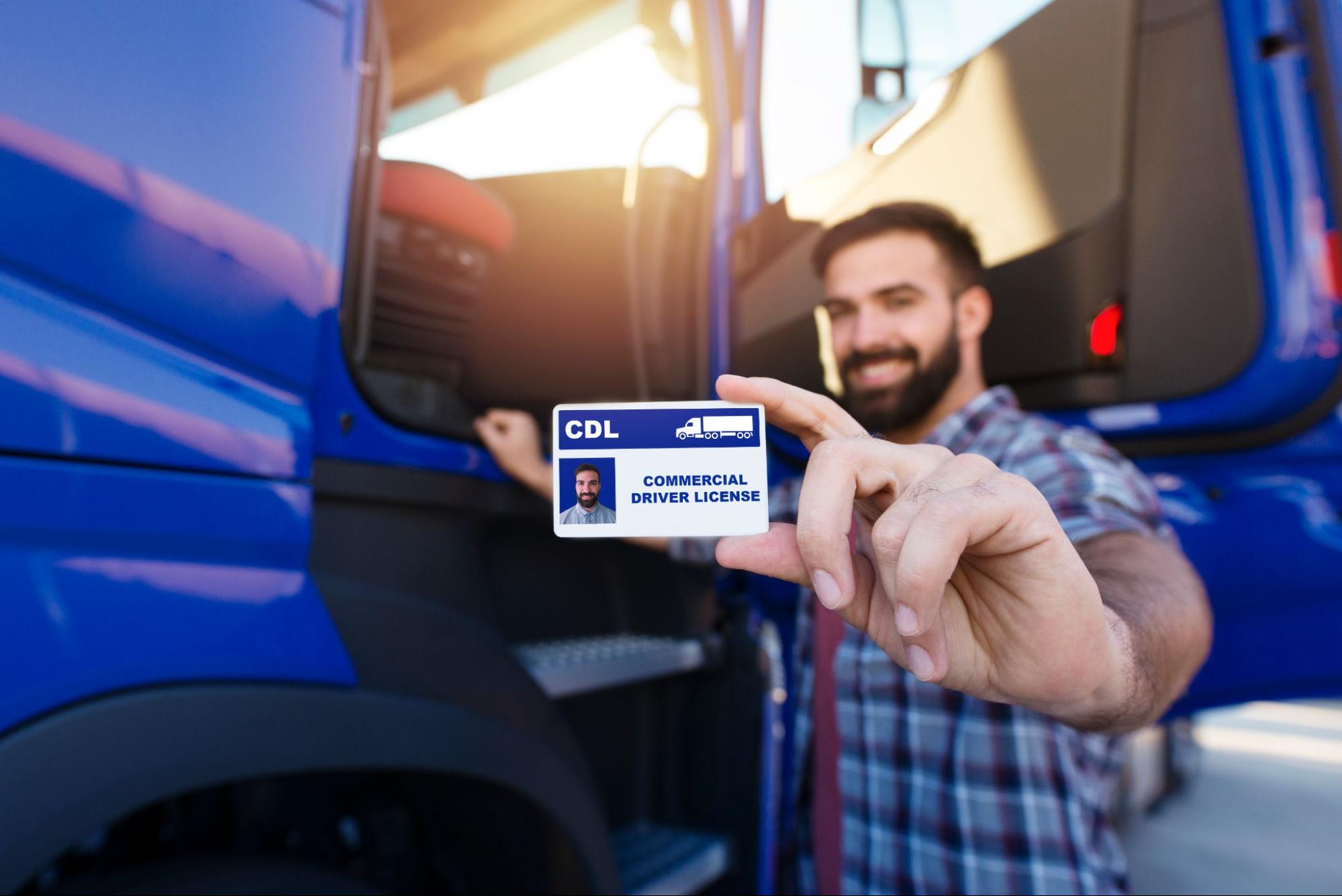 A man in front of a semi truck holding his CDL license 