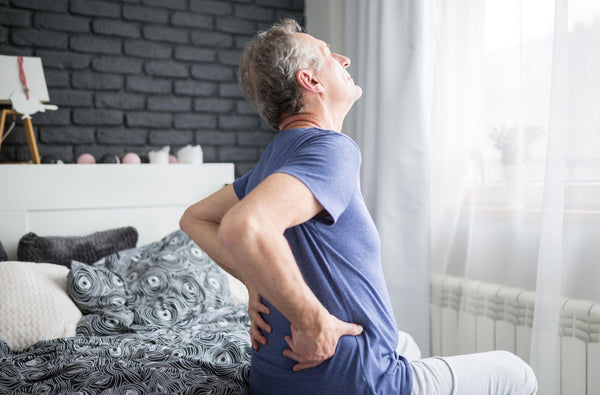 Man getting out of bed clutching his back