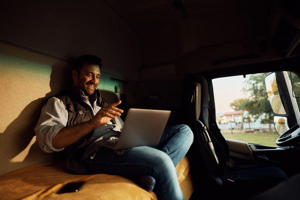Semi truck driver sitting on a mattress in the back of his cab relaxing