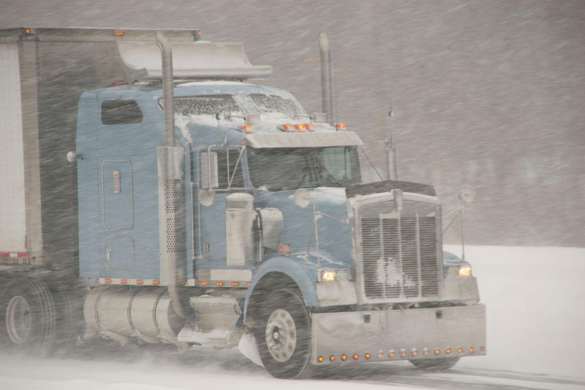 Semi truck driving through a snow storm