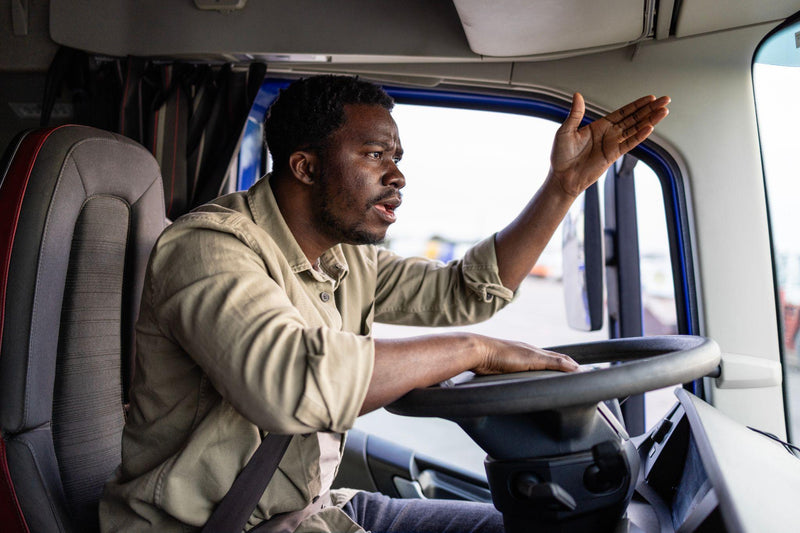 Shot of mad and nervous professional truck driver having arguing in traffic and yelling at someone.