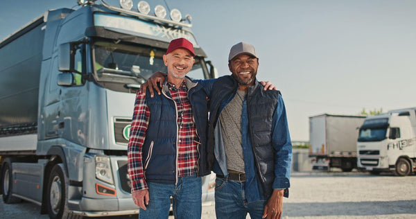 Team truck drivers smiling and posing in front of their truck