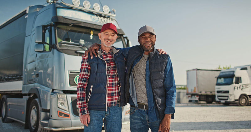Team truck drivers smiling and posing in front of their truck
