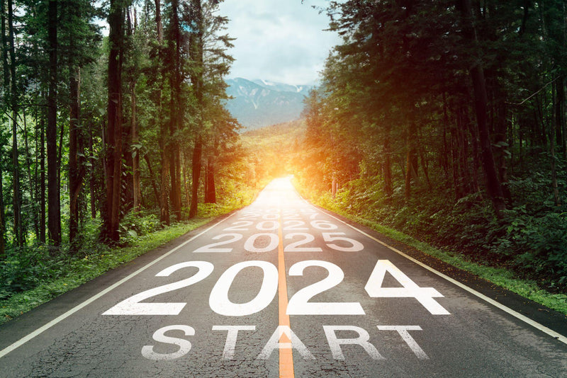 Text 2024 written on the middle of paved road with sunset.