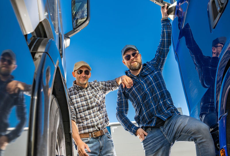 Two happy caucasian semi truck driver enjoying their driving job