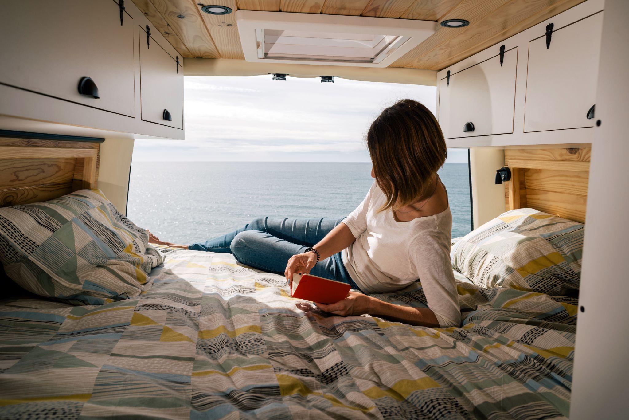 Woman in the back of a camper van reading
