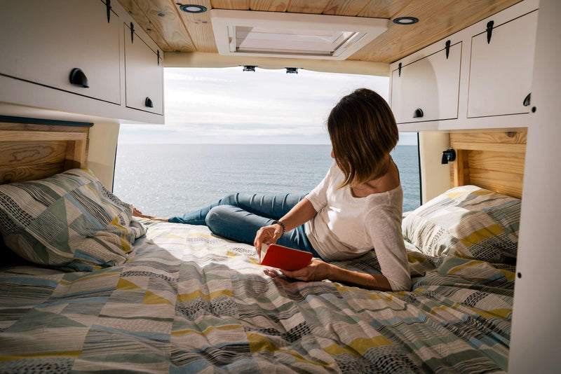 Woman in the back of a camper van reading