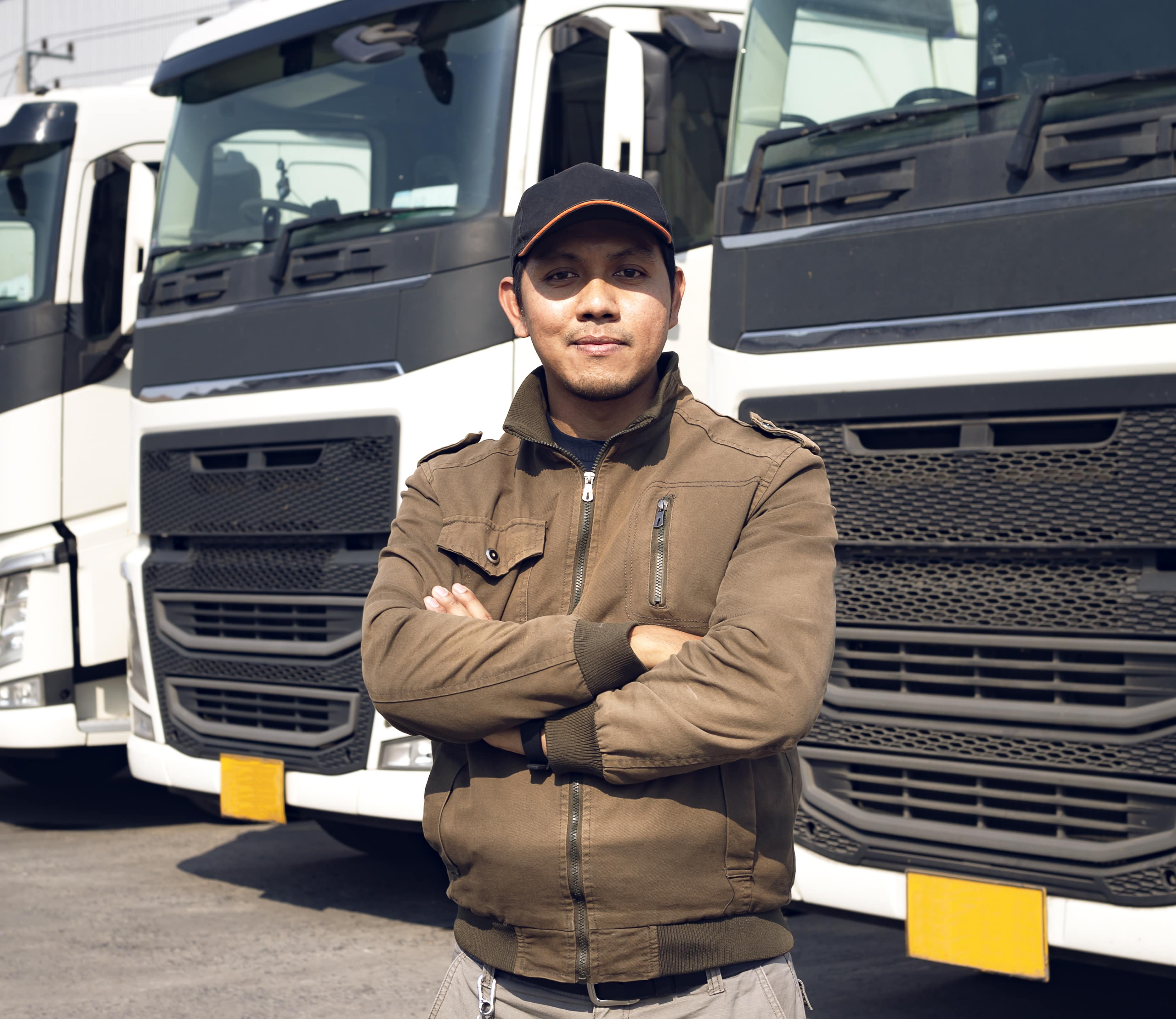 portrait of a truck driver standing in front of truck lineup